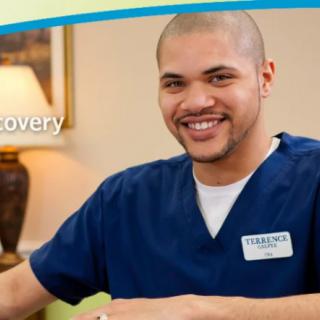 A smiling healthcare worker in scrubs, providing care.