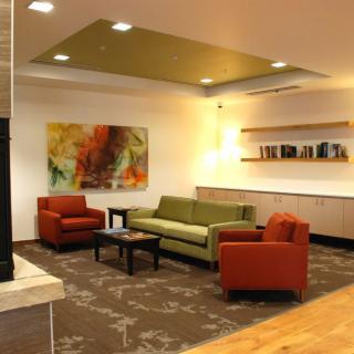 A modern living room with colorful sofas, artwork, and stylish shelving.