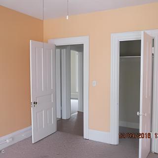 An interior room with orange walls, featuring open doors and a closet.