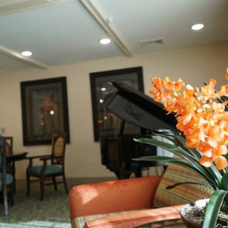 A cozy interior space featuring a piano, elegant chairs, and vibrant orange flowers.