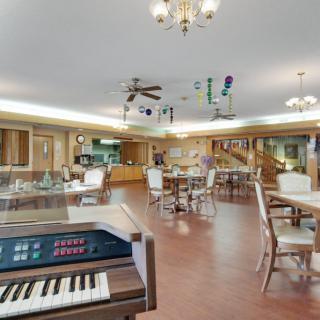 A spacious dining area featuring a piano, tables, and chairs under elegant lighting.