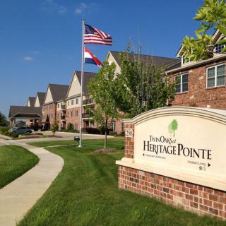 A suburban apartment complex with a prominent sign and flags waving in the breeze.