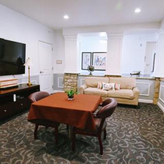 A cozy living room featuring a sofa, television, and a table with chairs on a patterned carpet.