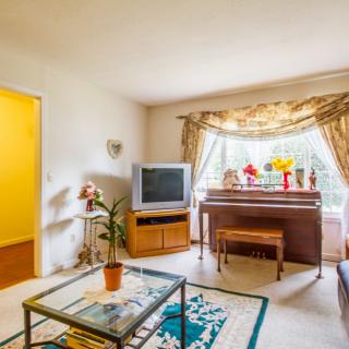 A cozy living room featuring a television and piano, accented with decorative items and curtains.