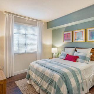 A cozy bedroom with striped bedding and colorful artwork above the headboard.