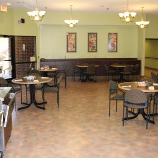 A well-lit dining area with tables and chairs, featuring decorative wall art.