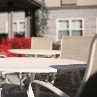 A sunny outdoor patio with tables and chairs in front of a building.