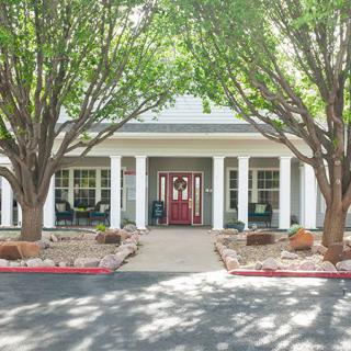 A building entrance with a welcoming front door and surrounding trees.