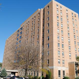 A tall residential building with a brick facade, set against a clear blue sky.