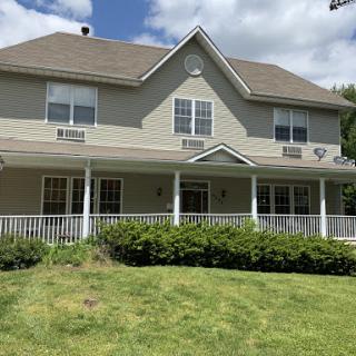 A two-story residential house with a welcoming porch and well-maintained yard.