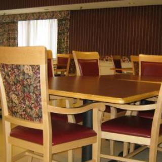 A dining area with wooden tables and chairs featuring patterned upholstery.