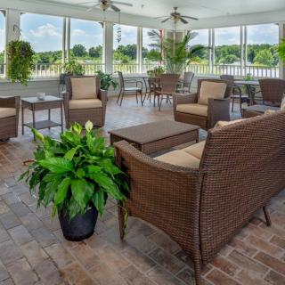 A cozy and elegant outdoor seating area with wicker furniture and lush greenery on a screened patio.