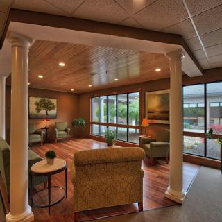 A cozy lounge area with comfortable seating, large windows allowing natural light, and decorative columns.