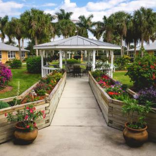 A picturesque garden scene featuring a gazebo surrounded by vibrant flowers and lush greenery.