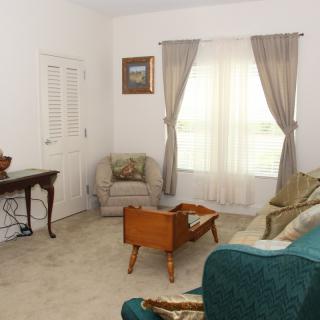 A cozy living room with a sofa, chair, and table near a window with curtains.