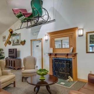 A cozy living room with a unique decor, featuring a sleigh hung from the ceiling and a classic fireplace.