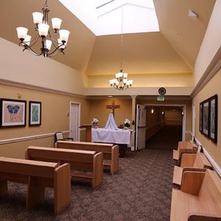 A serene chapel interior with wooden pews and an altar under soft lighting.