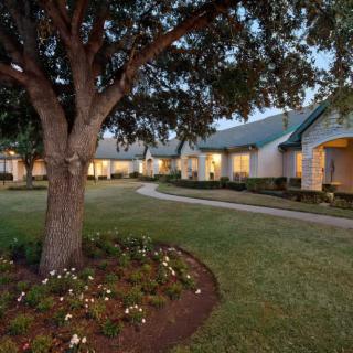 A picturesque house with a landscaped garden and tree at twilight.