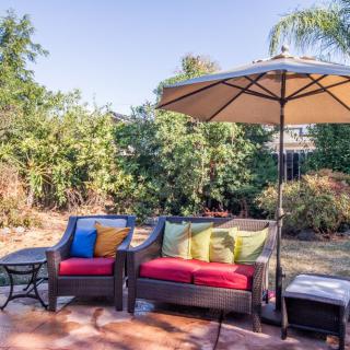 A cozy backyard patio with comfortable seating and a large umbrella on a sunny day.