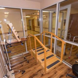 A physical therapy room equipped with a wooden ramp and various rehabilitation equipment.