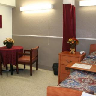 A cozy bedroom with a bed, small table, chairs, and decorative flowers.