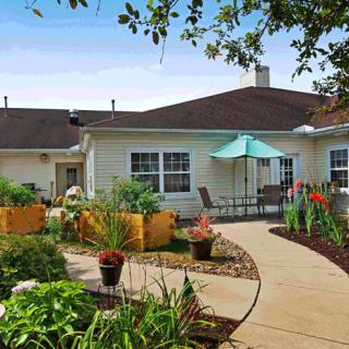A well-maintained garden with a pathway leads to a cozy building patio.