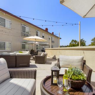 A cozy outdoor patio with comfortable seating and umbrellas on a sunny day, perfect for relaxation.