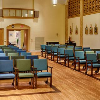 An interior view of a church with neatly arranged chairs and wooden flooring.
