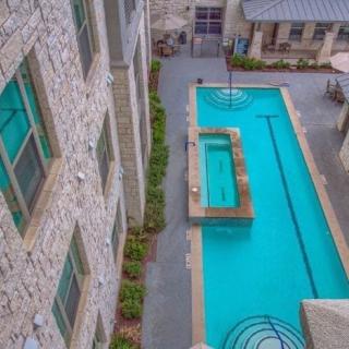 Aerial view of a swimming pool in an outdoor courtyard, surrounded by stone buildings.