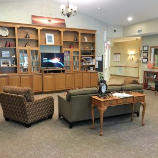 A cozy living room with a television, sofas, and decorative shelves.