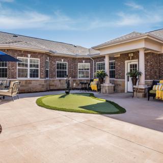 A well-maintained outdoor courtyard with a brick building, seating areas, and landscaping.