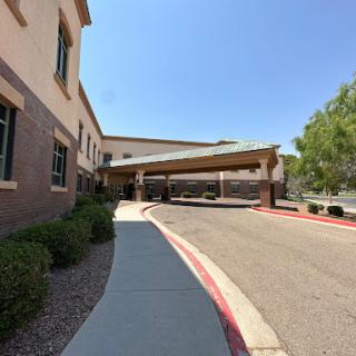 A view of the entrance to a building with a covered area and a well-maintained sidewalk.