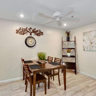A cozy dining area featuring a wooden table set with chairs, decorative plants, and artwork on the walls.