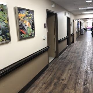 A well-lit hallway featuring colorful paintings on the walls and a wooden floor.