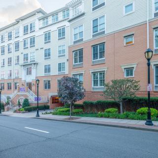 A modern residential building along a quiet urban street with landscaping and lamp posts.