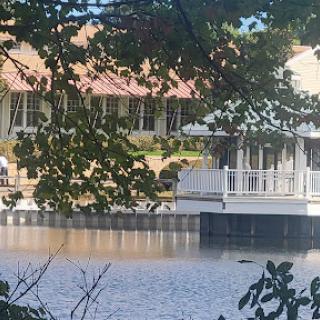 A serene view of a waterfront building framed by lush greenery.