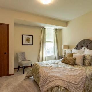 A cozy and well-decorated bedroom with a neatly made bed, stylish lamp, and elegant curtains.