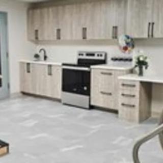 A modern kitchen with light wood cabinets and a stainless steel stove.