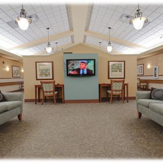 A spacious living room with comfortable seating, tables, and a television under elegant lighting.