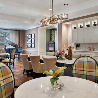 A modern dining and kitchen area with stylish furniture and a grand piano in the background.