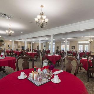 Elegant dining room with red tablecloths and chandeliers.
