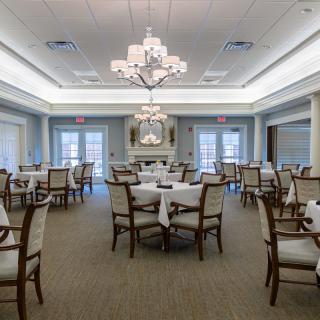 Elegant dining room with neatly arranged tables and chandeliers.