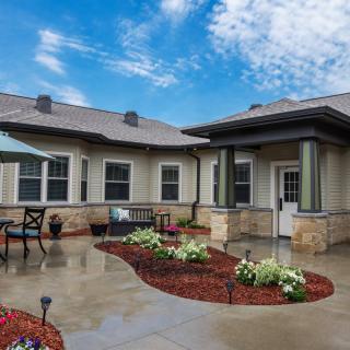 A well-maintained house with a landscaped patio and garden under a bright blue sky.