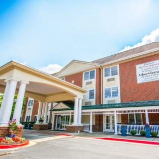 A hotel entrance with a covered driveway and columns under a clear blue sky.