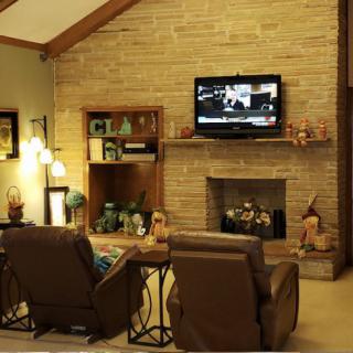 A cozy living room with a brick fireplace, TV, and comfortable armchairs.
