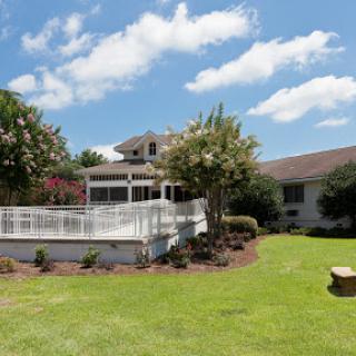 A beautiful home with a spacious patio and well-maintained garden under a bright blue sky.