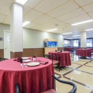 An indoor restaurant dining area with tables covered in red tablecloths.