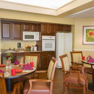 A cozy kitchen and dining area with wooden cabinetry, equipped with modern appliances and neatly set tables.