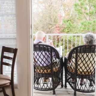 Two elderly individuals seated on a balcony, enjoying a peaceful moment together.