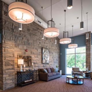 A modern living room with a stone wall, featuring pendant lighting and comfortable seating.